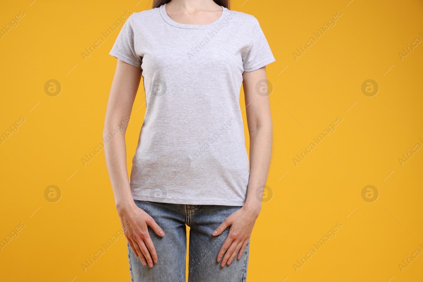 Photo of Woman wearing blank white t-shirt on orange background, closeup. Mockup for design