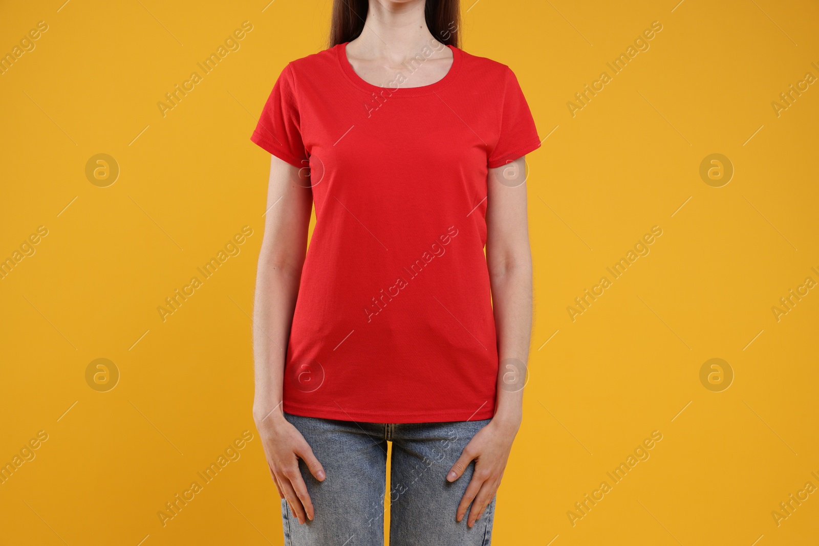 Photo of Woman wearing blank red t-shirt on orange background, closeup. Mockup for design