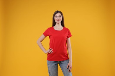 Photo of Woman wearing blank red t-shirt on orange background. Mockup for design