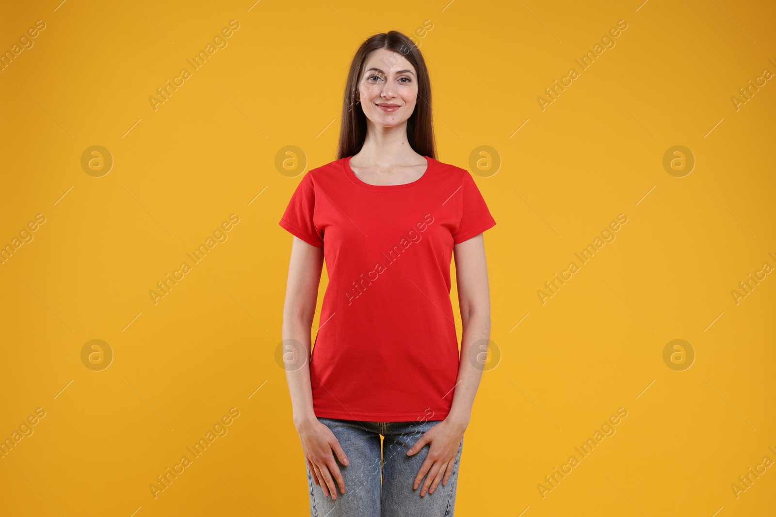 Photo of Woman wearing blank red t-shirt on orange background. Mockup for design