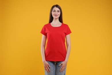 Photo of Woman wearing blank red t-shirt on orange background. Mockup for design