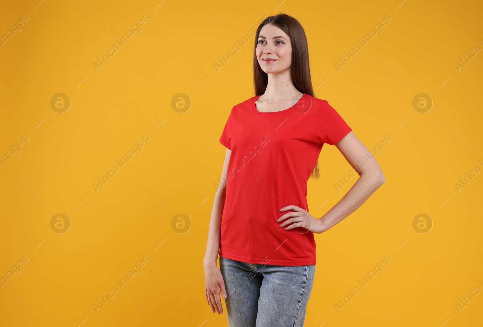 Photo of Woman wearing blank red t-shirt on orange background. Mockup for design