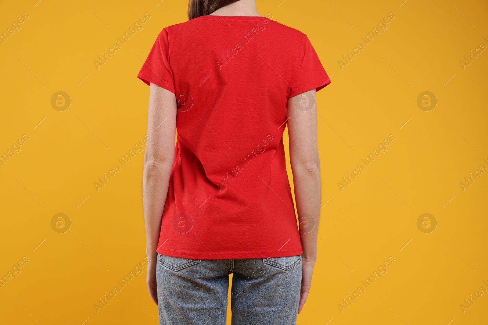 Photo of Woman wearing blank red t-shirt on orange background, back view. Mockup for design