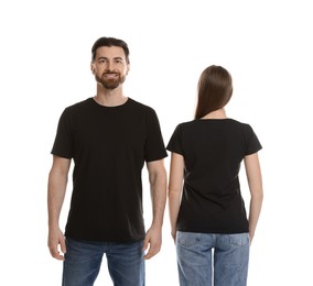 Photo of Woman and man wearing blank black t-shirts on white background. Mockup for design