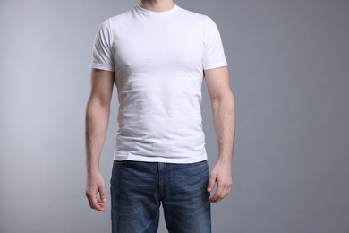 Photo of Man wearing blank white t-shirt on light grey background, closeup. Mockup for design