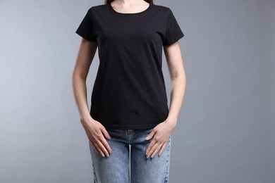 Photo of Woman wearing blank black t-shirt on light grey background, closeup. Mockup for design