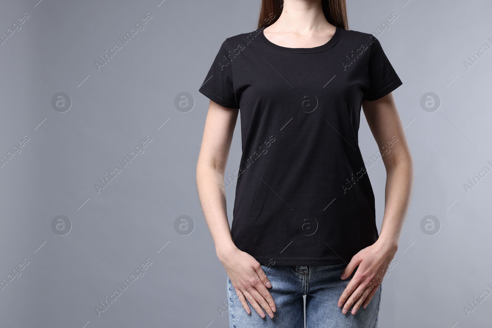 Photo of Woman wearing blank black t-shirt on light grey background, closeup. Mockup for design