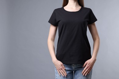 Photo of Woman wearing blank black t-shirt on light grey background, closeup. Mockup for design