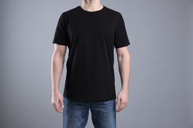 Photo of Man wearing blank black t-shirt on light grey background, closeup. Mockup for design