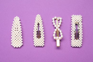 Photo of Different hair clips on purple background, flat lay