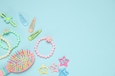 Photo of Different hair accessories and brush on light blue background, flat lay. Space for text