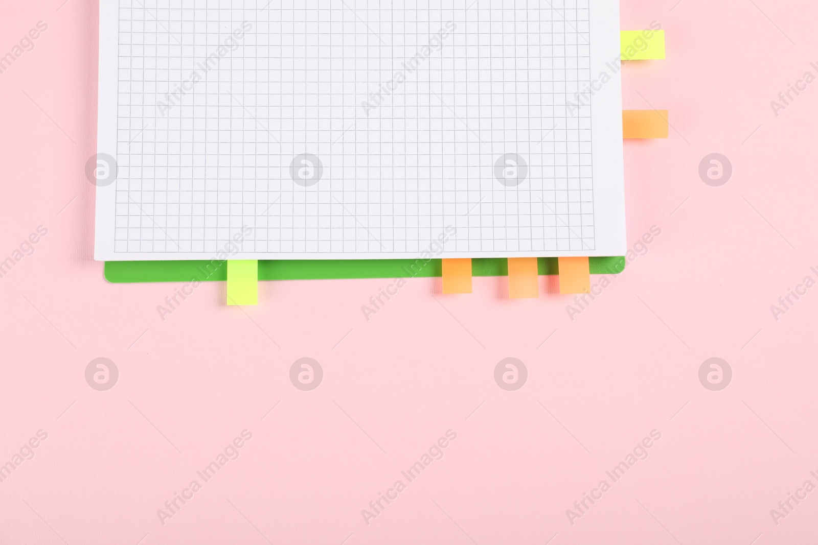 Photo of Notebook with colorful tabs on pink background, top view. Space for text