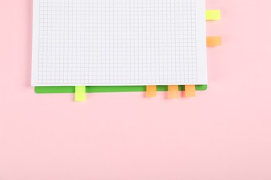 Photo of Notebook with colorful tabs on pink background, top view. Space for text