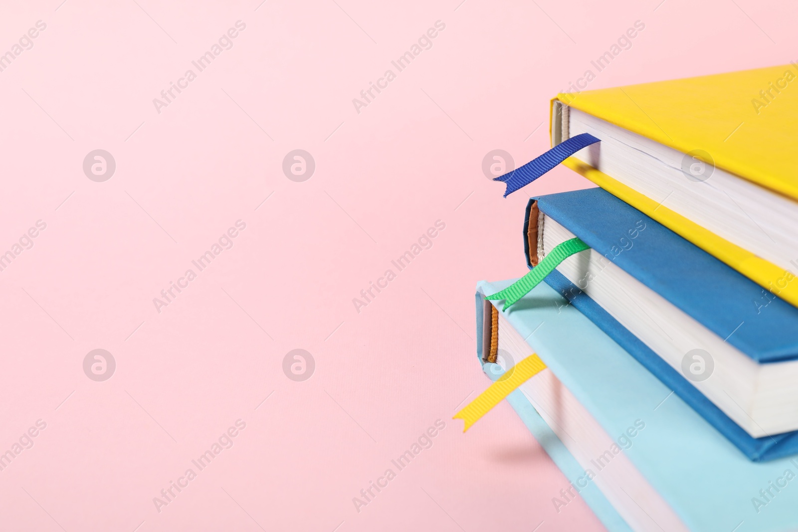 Photo of Books with ribbon bookmarks on pink background, closeup. Space for text