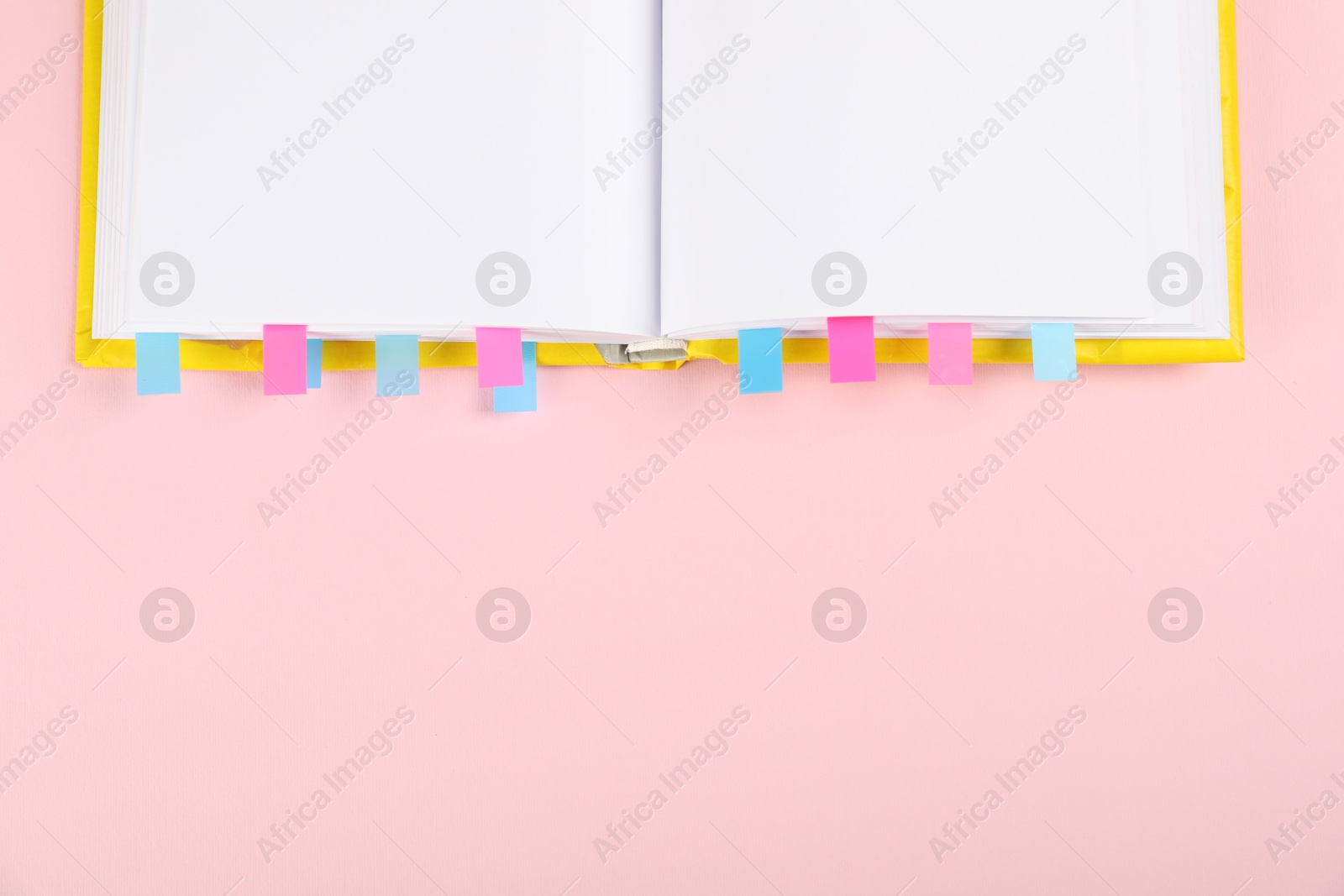 Photo of Book with colorful tabs on pink background, top view. Space for text