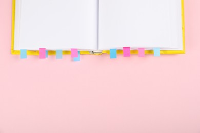 Photo of Book with colorful tabs on pink background, top view. Space for text