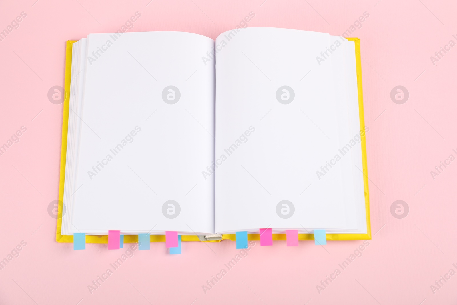 Photo of Book with colorful tabs on pink background, top view