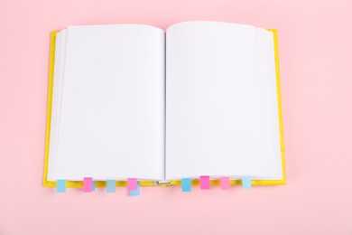 Photo of Book with colorful tabs on pink background, top view