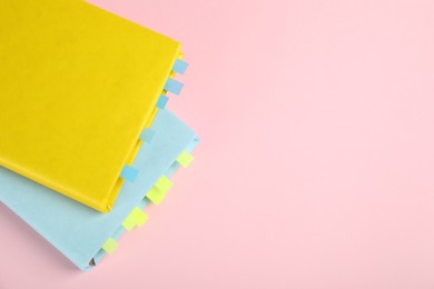 Photo of Books with colorful tabs on pink background, top view. Space for text