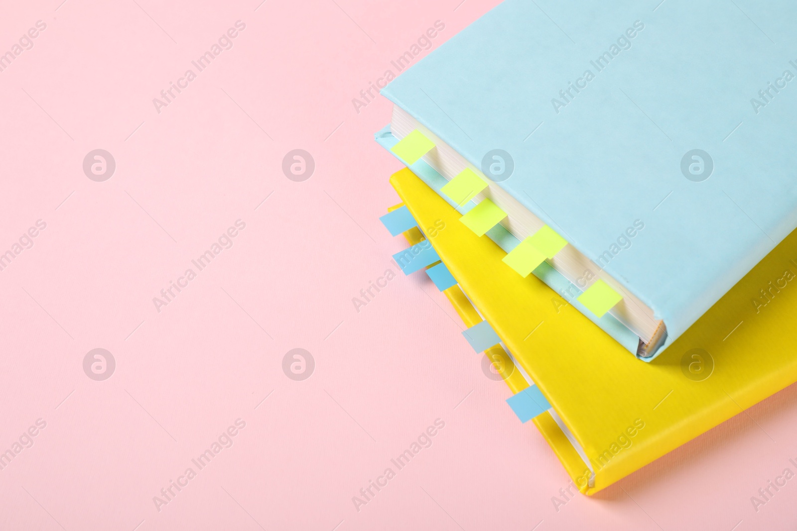 Photo of Books with colorful tabs on pink background, closeup. Space for text