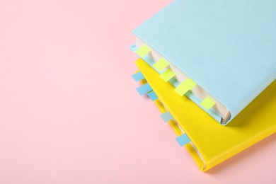 Photo of Books with colorful tabs on pink background, closeup. Space for text