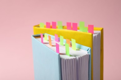 Photo of Books with colorful tabs on pink background, closeup