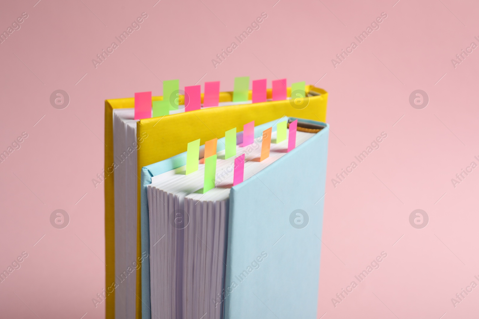 Photo of Books with colorful tabs on pink background, closeup