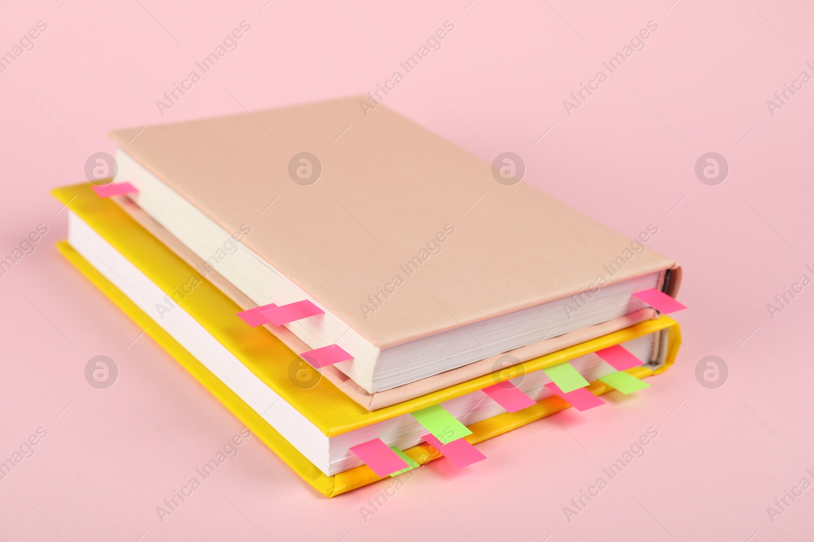 Photo of Books with colorful tabs on pink background, closeup