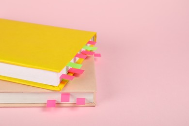 Photo of Books with colorful tabs on pink background, closeup. Space for text