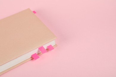 Photo of Book with colorful tabs on pink background, closeup. Space for text