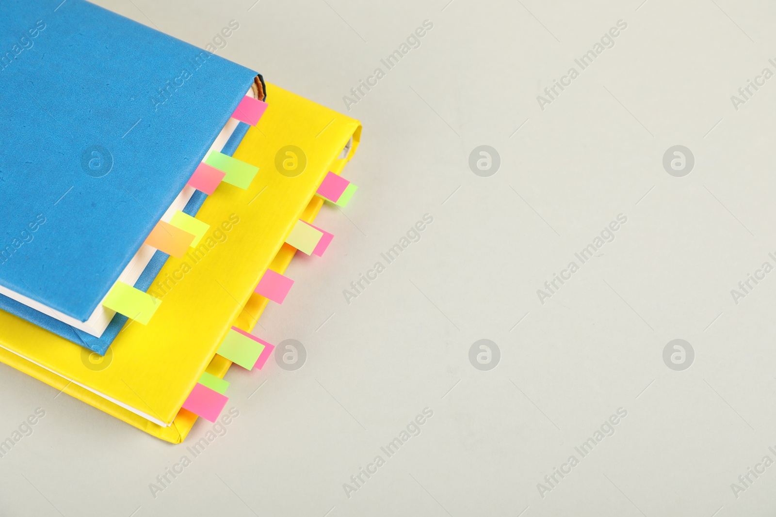 Photo of Books with colorful tabs on light gray background, above view. Space for text