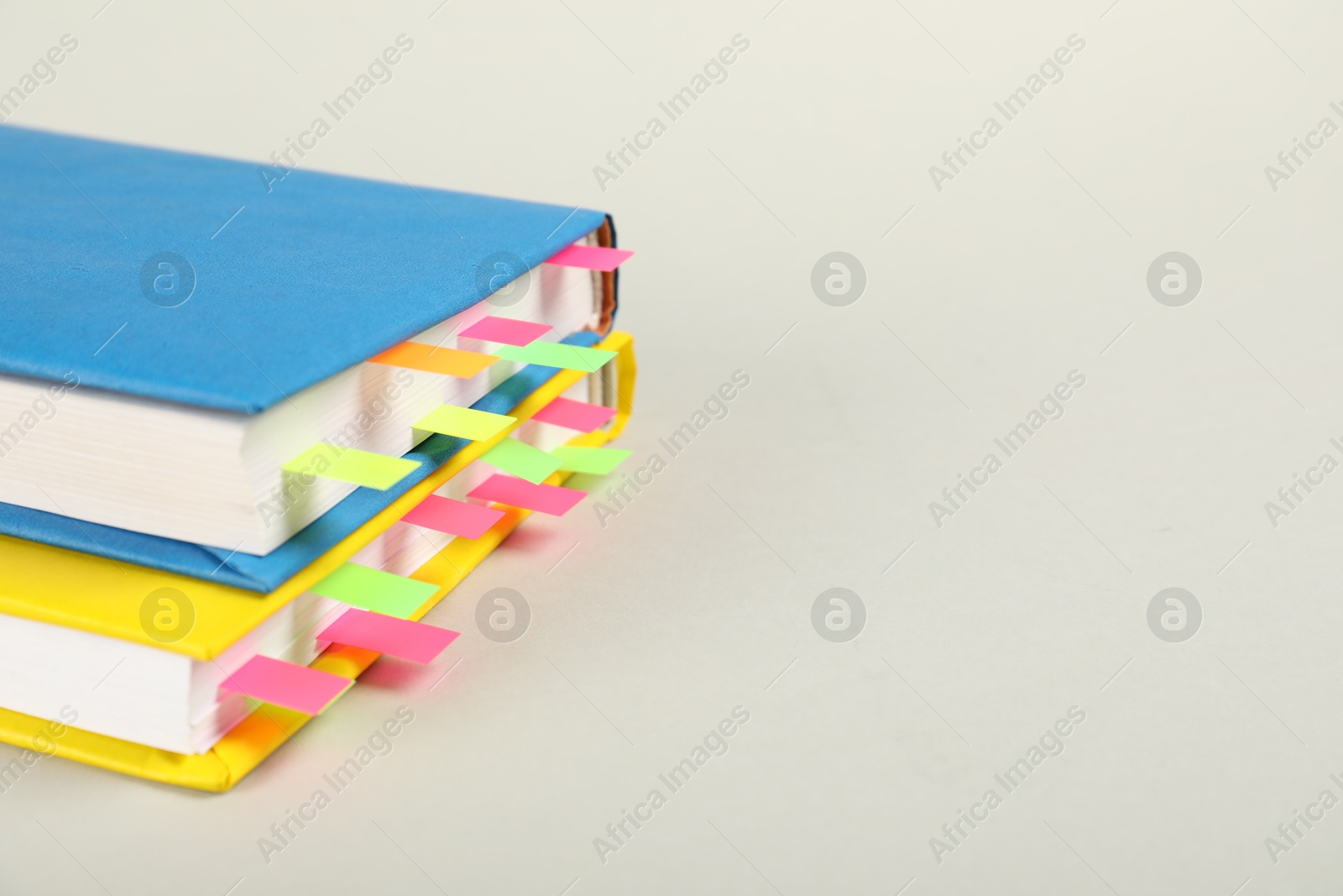 Photo of Books with colorful tabs on light gray background, closeup. Space for text