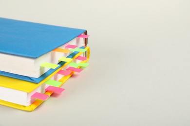 Photo of Books with colorful tabs on light gray background, closeup. Space for text