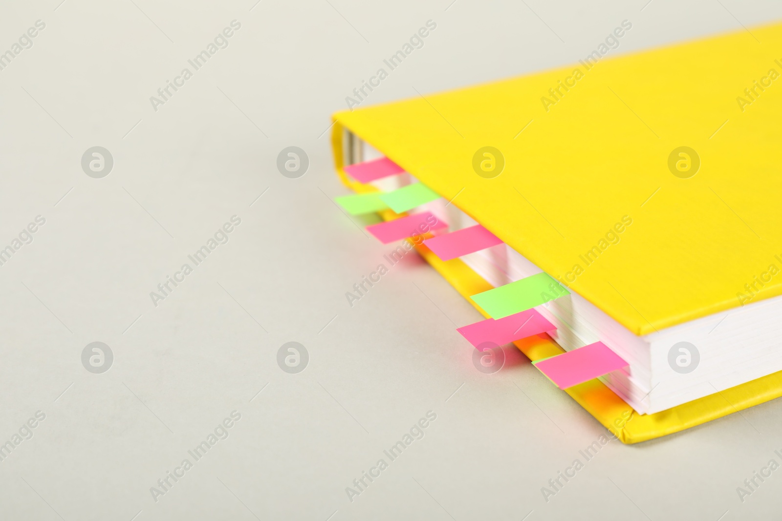 Photo of Book with colorful tabs on light gray background, closeup. Space for text