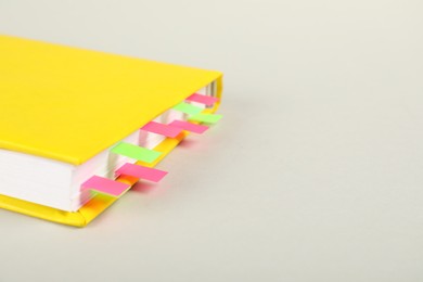 Photo of Book with colorful tabs on light gray background, closeup. Space for text