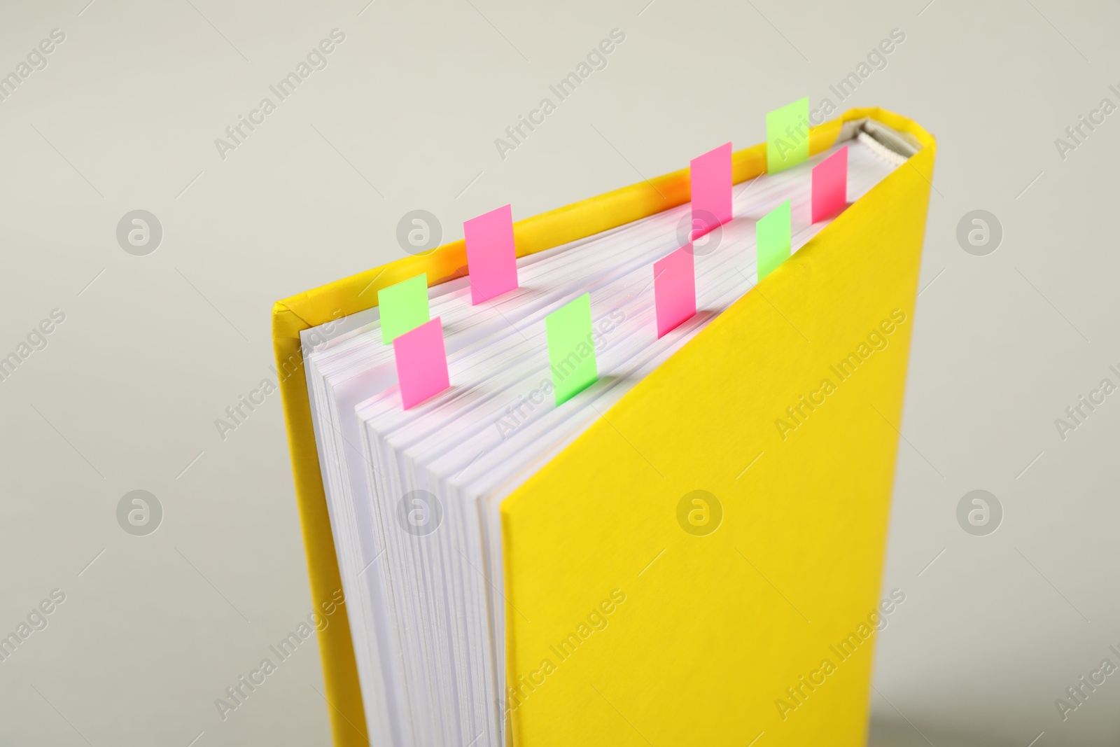 Photo of Book with colorful tabs on light gray background, closeup