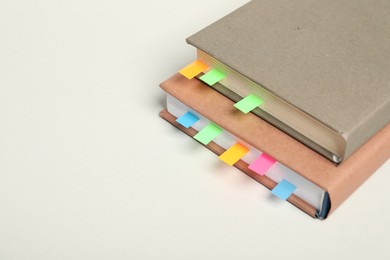 Photo of Books with colorful tabs on light gray background, closeup. Space for text