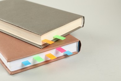 Photo of Books with colorful tabs on light gray background, closeup. Space for text