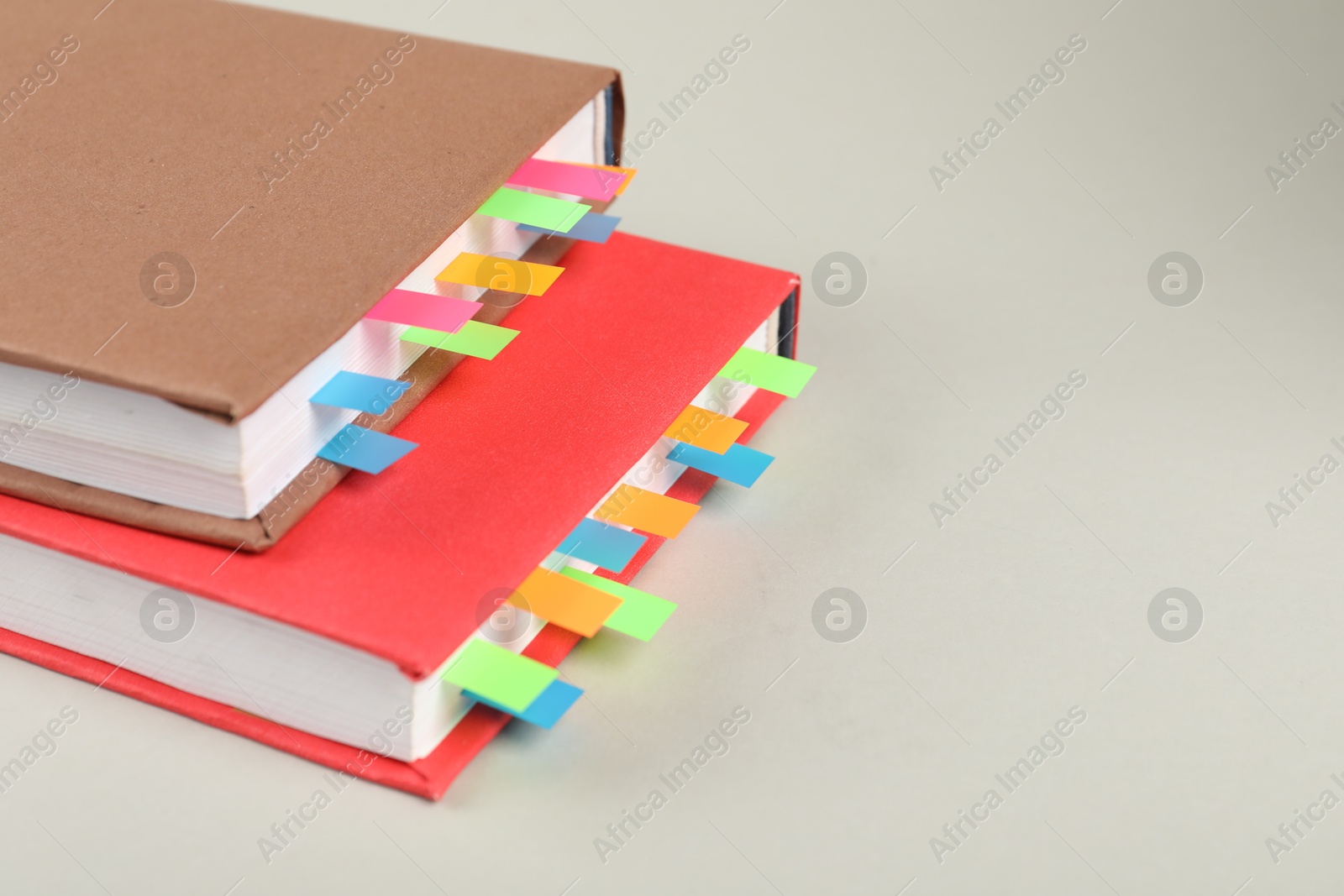 Photo of Books with colorful tabs on light gray background, closeup. Space for text