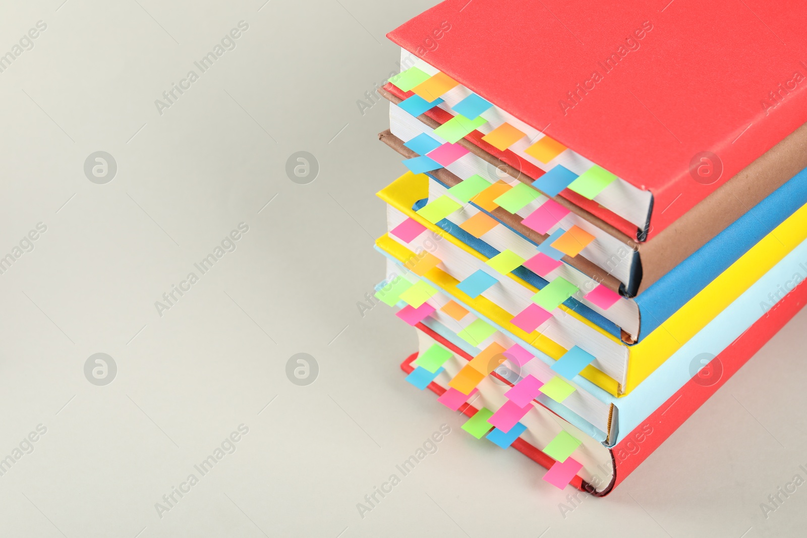 Photo of Books with colorful tabs on light gray background, closeup. Space for text