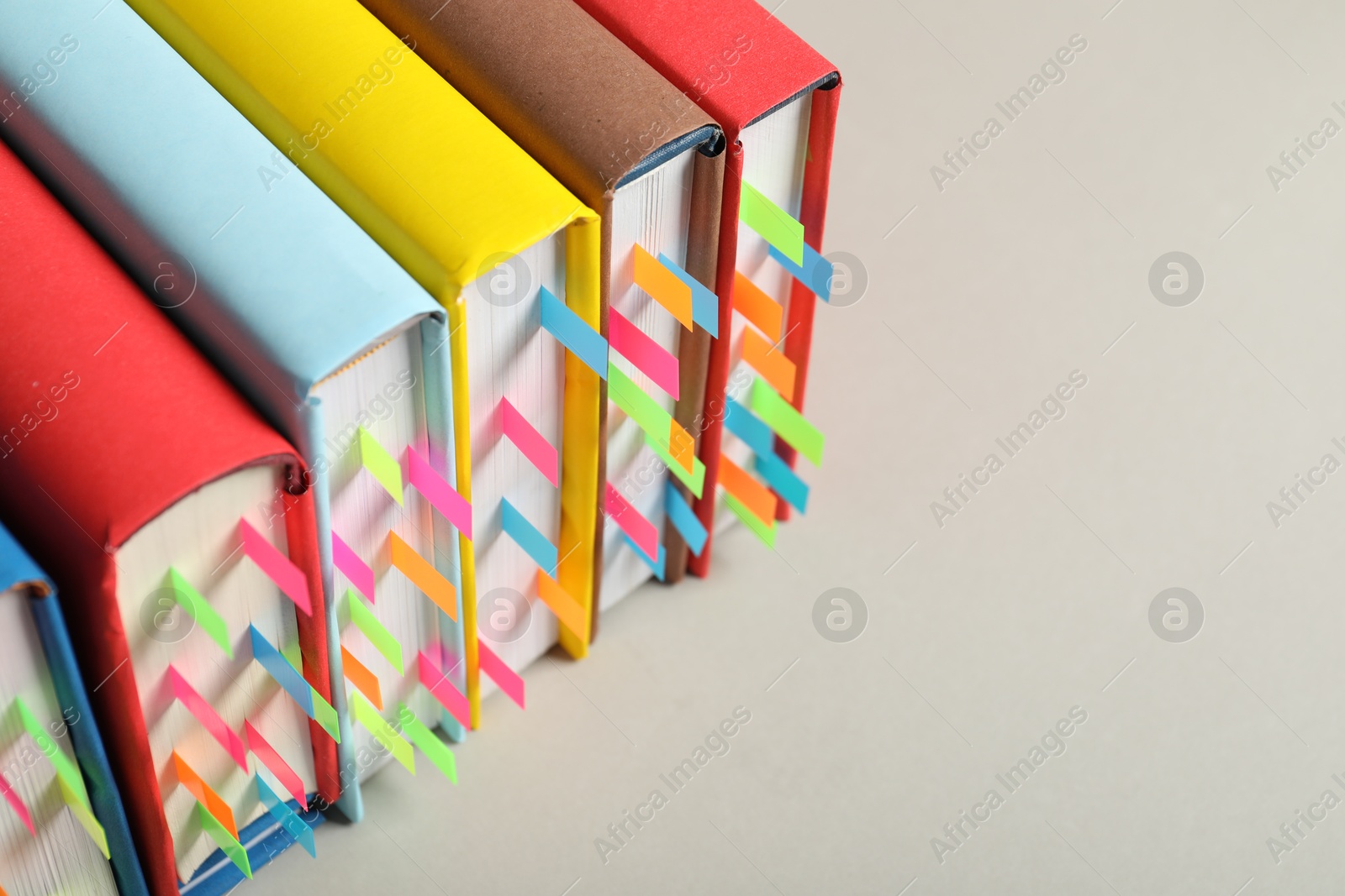 Photo of Books with colorful tabs on light gray background, closeup. Space for text