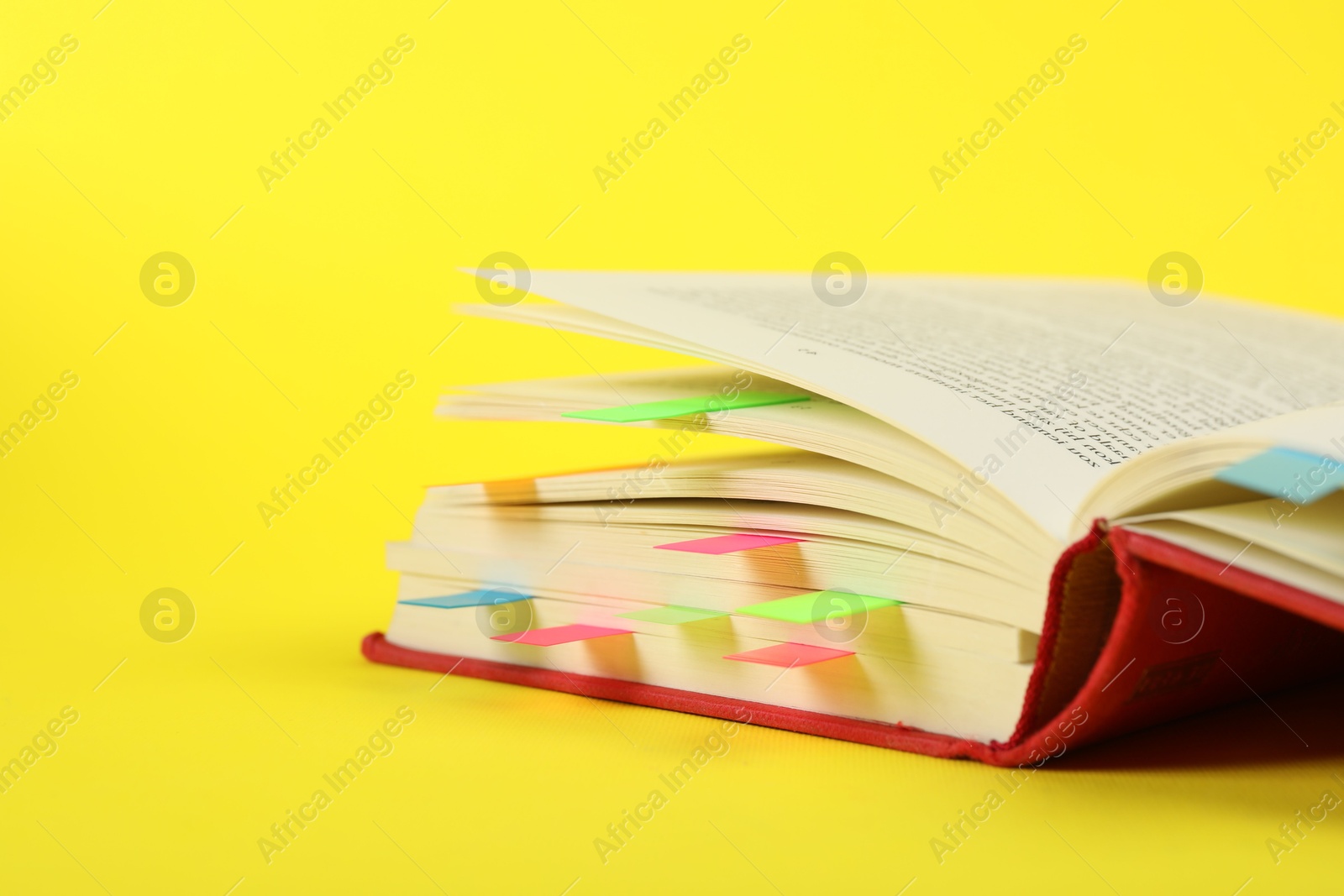 Photo of Book with colorful tabs on yellow background, closeup. Space for text