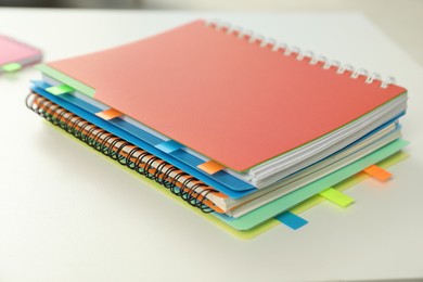 Photo of Notebooks with colorful tabs on light table, closeup