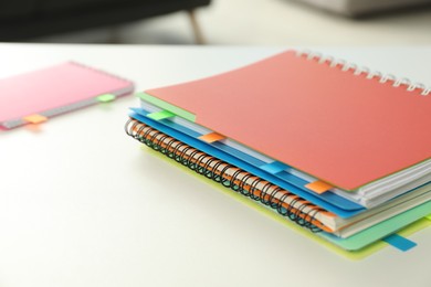 Photo of Notebooks with colorful tabs on light table, closeup