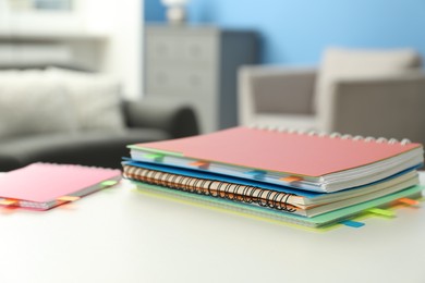 Photo of Notebooks with colorful tabs on light table indoors, closeup