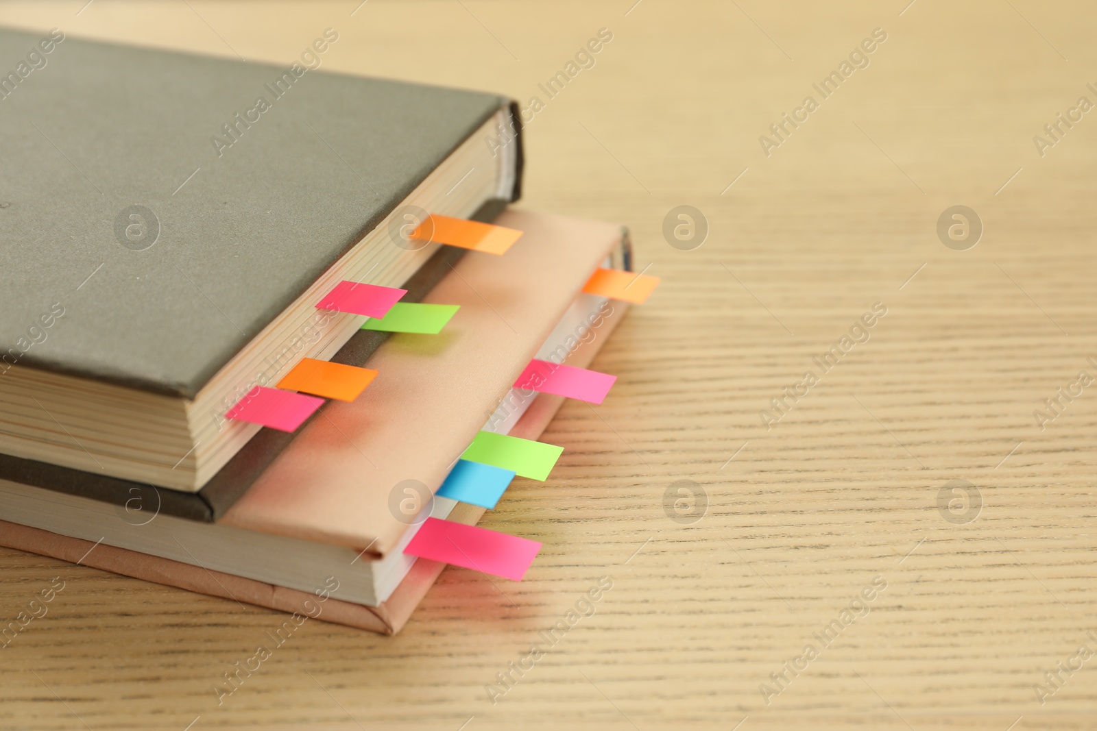 Photo of Books with colorful tabs on wooden table, closeup. Space for text