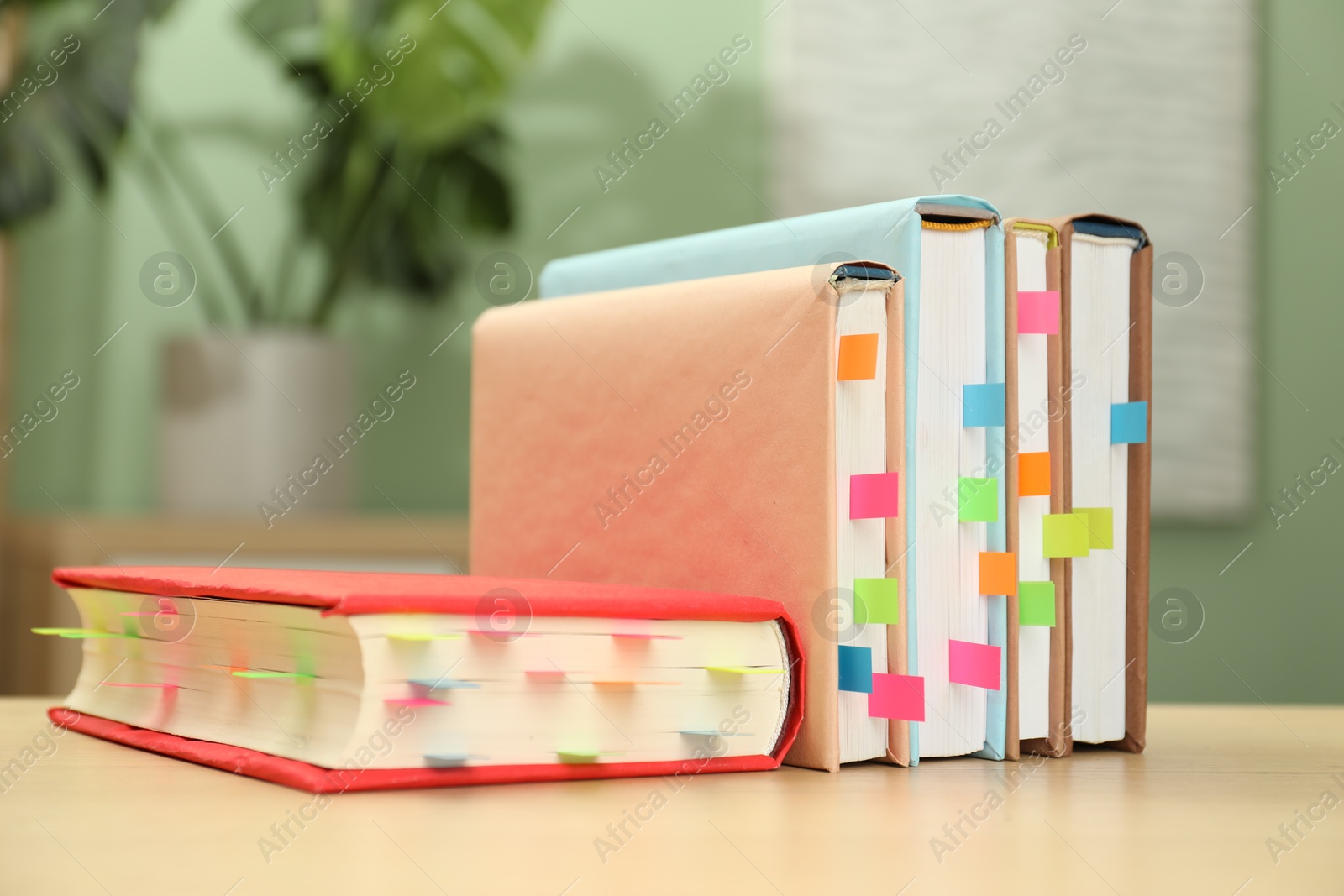 Photo of Books with colorful tabs on wooden table indoors