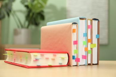 Photo of Books with colorful tabs on wooden table indoors