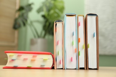 Photo of Books with colorful tabs on wooden table indoors