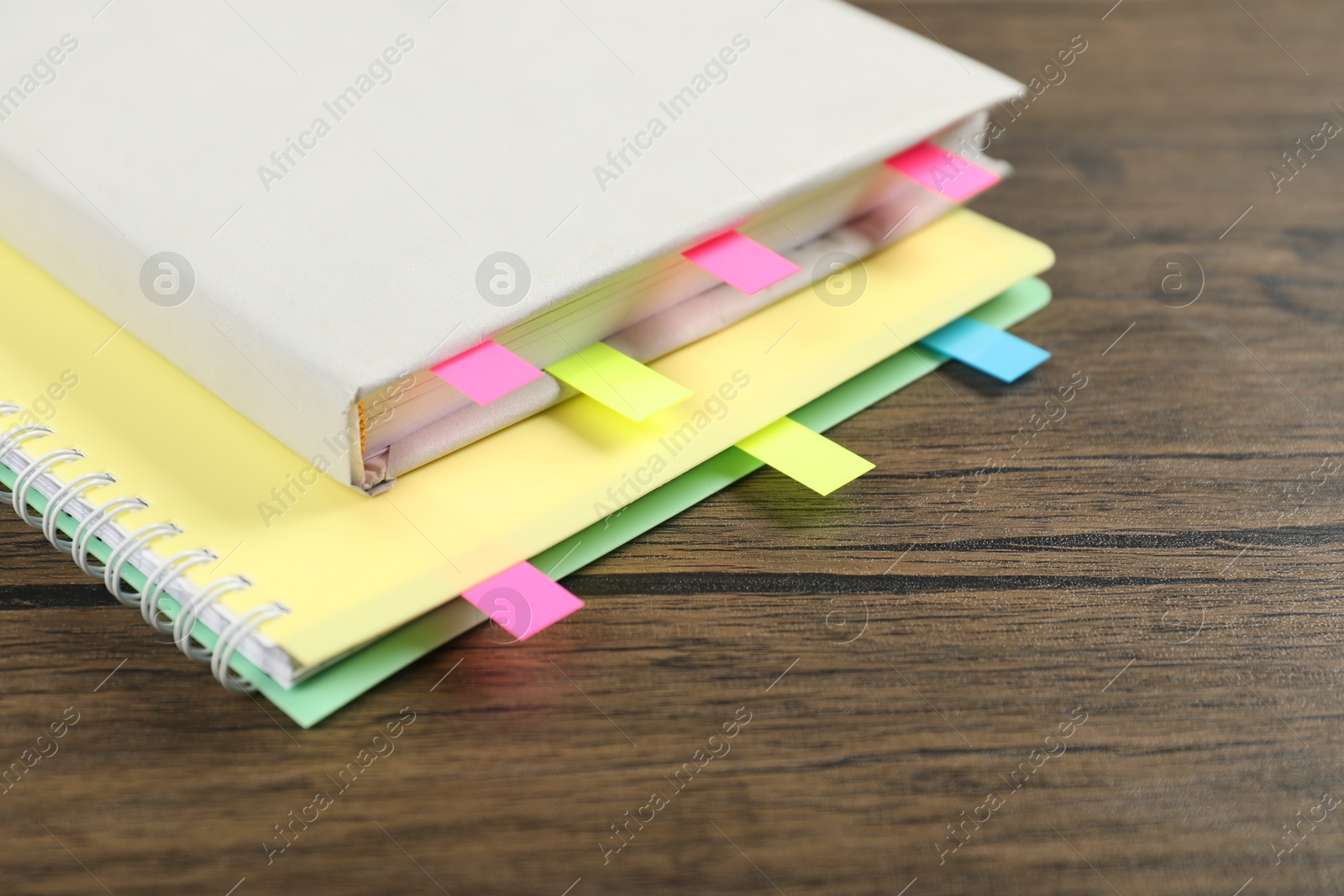 Photo of Book and notebook with colorful tabs on wooden table, closeup